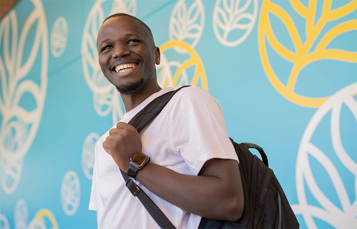 Smiling black male carrying a backpack