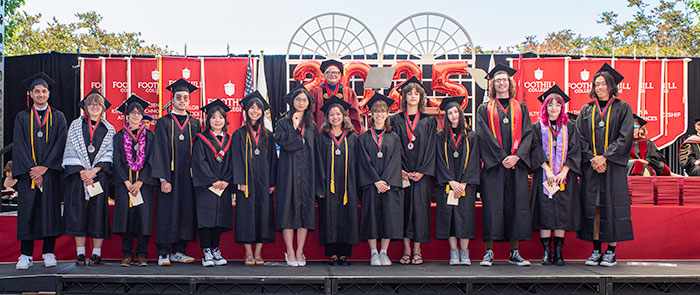 large group of graduates with presidents medals standing on stage with President Whalen